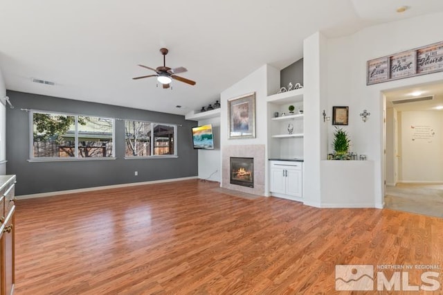 unfurnished living room featuring ceiling fan, wood-type flooring, a tile fireplace, and lofted ceiling