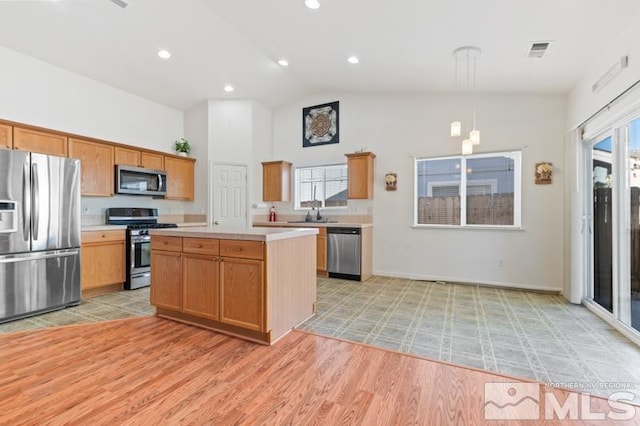 kitchen with stainless steel appliances, light hardwood / wood-style floors, high vaulted ceiling, hanging light fixtures, and a kitchen island