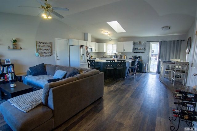 living room with dark hardwood / wood-style flooring, ceiling fan, and lofted ceiling with skylight