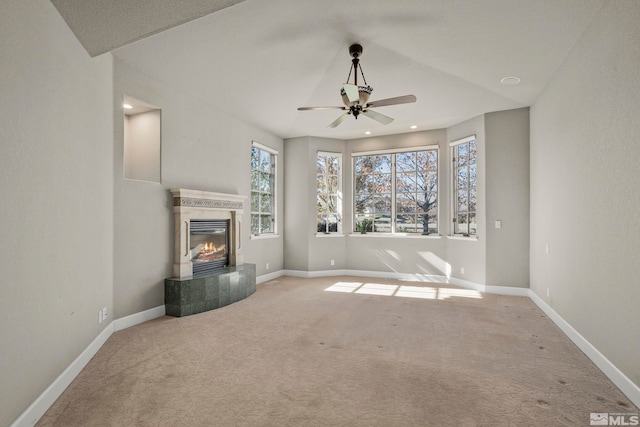 unfurnished living room featuring ceiling fan, a tiled fireplace, and carpet floors