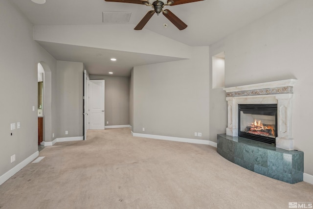 unfurnished living room featuring ceiling fan, vaulted ceiling, light carpet, and a premium fireplace