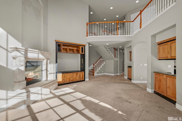 unfurnished living room featuring a high ceiling and light colored carpet