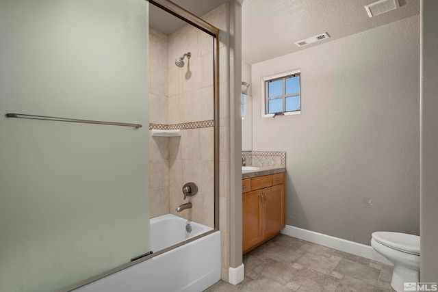 full bathroom featuring shower / bath combination with glass door, a textured ceiling, toilet, and vanity