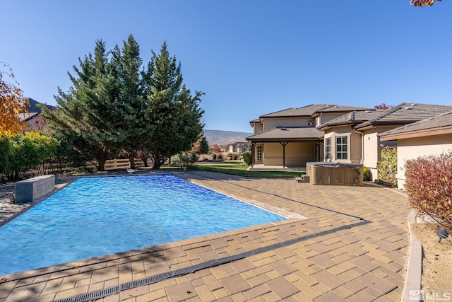 view of pool with a hot tub, a patio area, and a mountain view