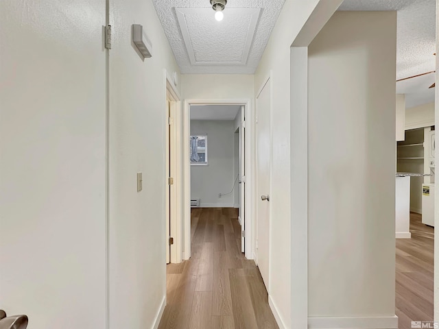 corridor with light hardwood / wood-style floors and a textured ceiling