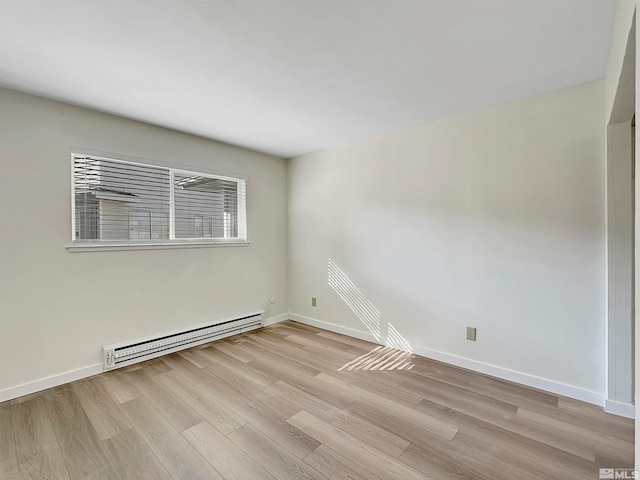 spare room with light wood-type flooring and a baseboard heating unit