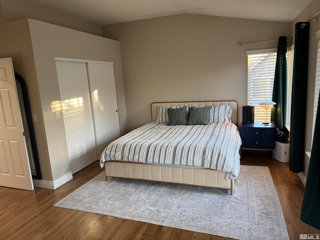 bedroom with dark wood-type flooring, a closet, and vaulted ceiling