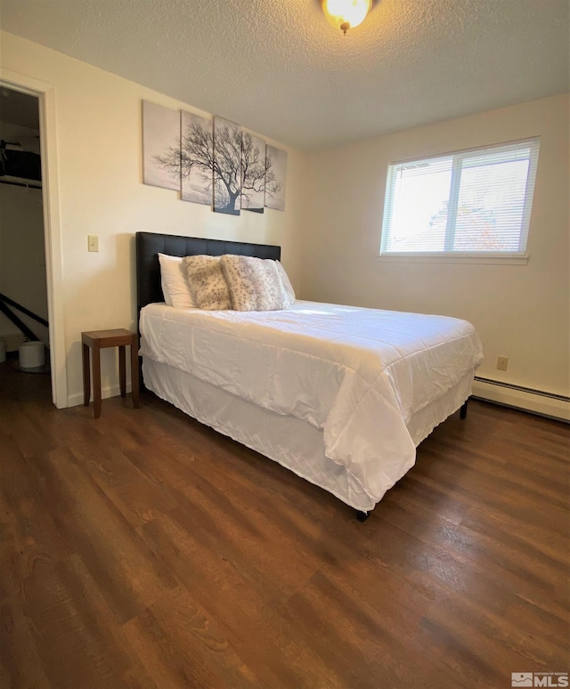 bedroom with a textured ceiling, dark hardwood / wood-style flooring, and baseboard heating