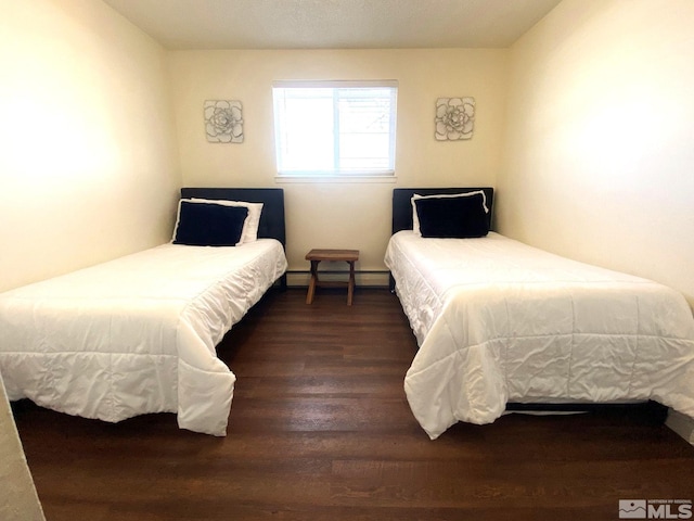 bedroom with dark wood-type flooring and a baseboard heating unit