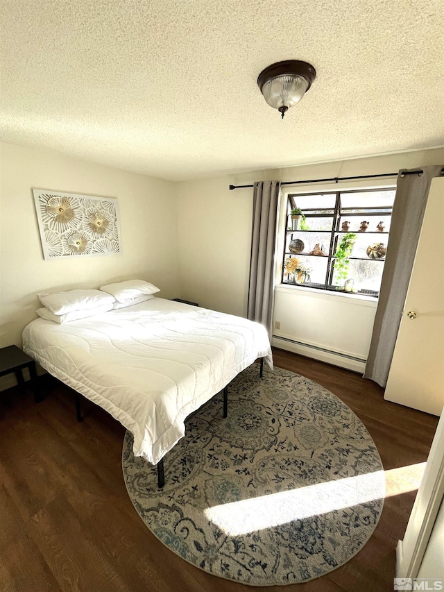 bedroom featuring dark hardwood / wood-style flooring, a textured ceiling, and a baseboard heating unit