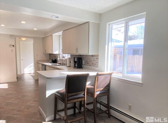 kitchen with white cabinets, a kitchen breakfast bar, sink, decorative backsplash, and kitchen peninsula