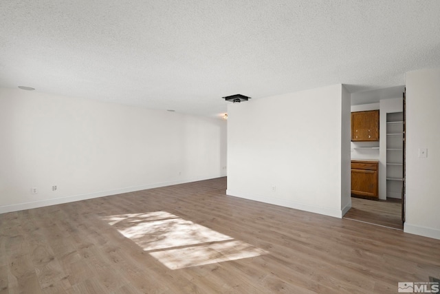 spare room featuring a textured ceiling and light hardwood / wood-style floors