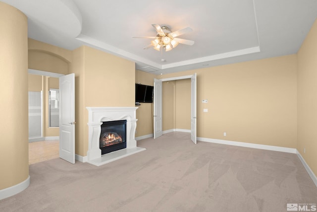 unfurnished living room featuring ceiling fan, light carpet, and a tray ceiling