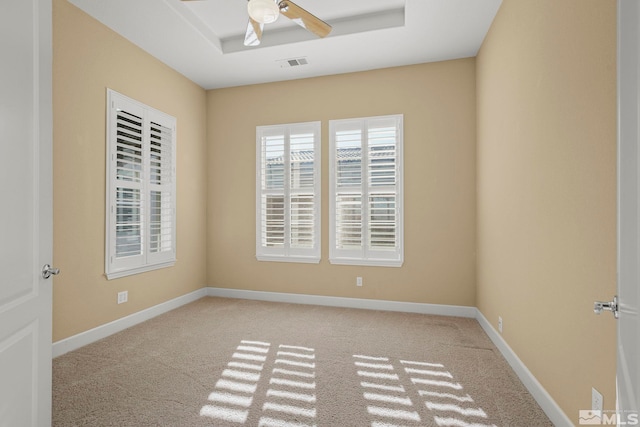 carpeted empty room featuring a tray ceiling and ceiling fan