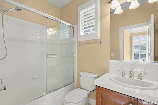 full bathroom featuring bath / shower combo with glass door, vanity, and toilet