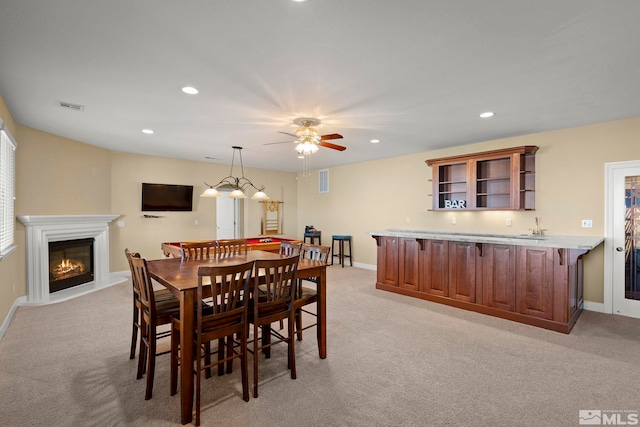 carpeted dining room with sink and ceiling fan