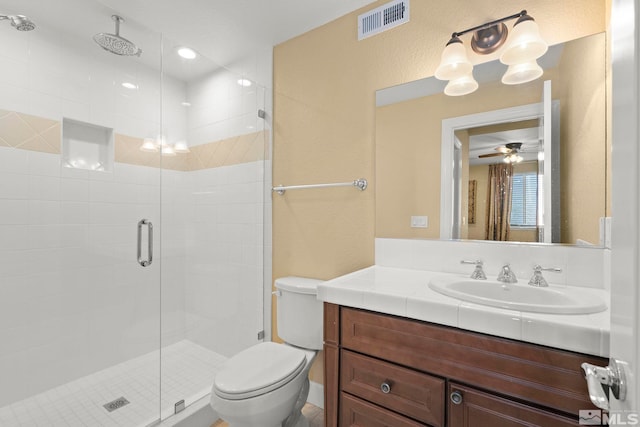 bathroom featuring vanity, ceiling fan, toilet, and a shower with door