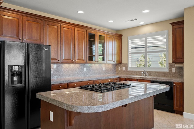 kitchen with black appliances, a kitchen island, a breakfast bar, and backsplash