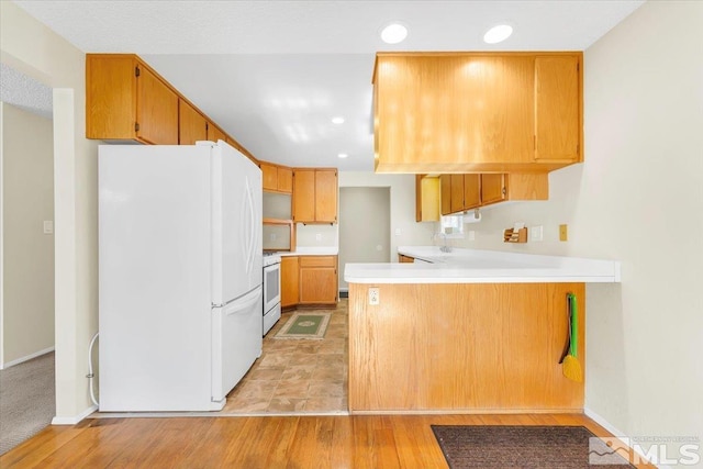 kitchen featuring kitchen peninsula, light hardwood / wood-style flooring, white appliances, and sink