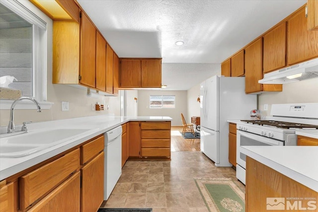 kitchen featuring white appliances, kitchen peninsula, sink, and a textured ceiling