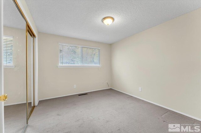 unfurnished bedroom featuring a textured ceiling, carpet floors, and a closet