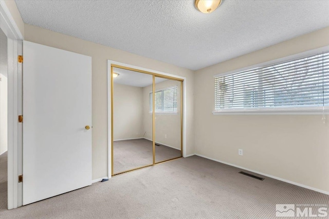 unfurnished bedroom with a closet, a textured ceiling, and carpet flooring