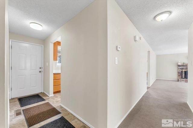 hall featuring light carpet and a textured ceiling