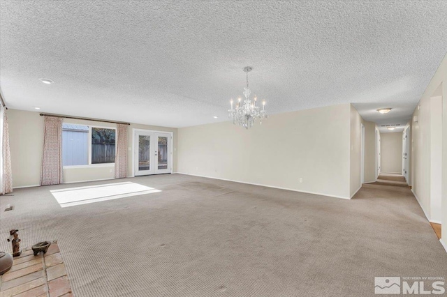 unfurnished living room featuring light colored carpet, a textured ceiling, and a notable chandelier