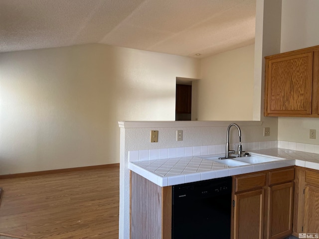 kitchen featuring a textured ceiling, sink, dishwasher, kitchen peninsula, and light hardwood / wood-style flooring