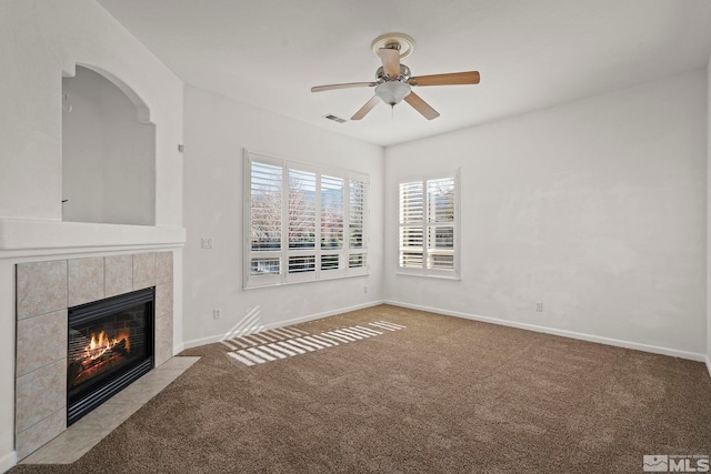 unfurnished living room featuring a tiled fireplace, light colored carpet, and ceiling fan