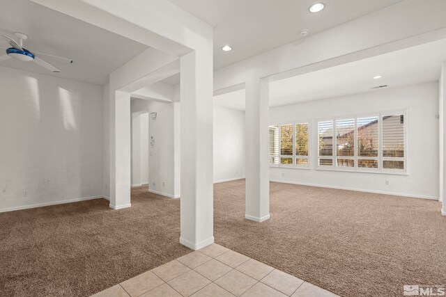 basement featuring light carpet and ceiling fan