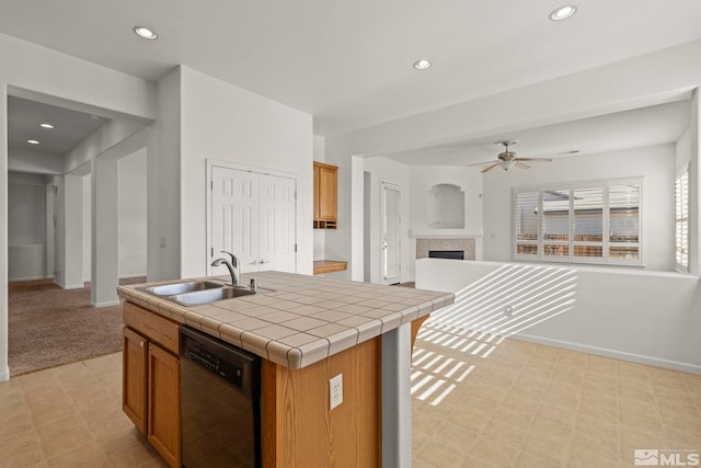 kitchen with a center island with sink, sink, a fireplace, tile counters, and dishwasher