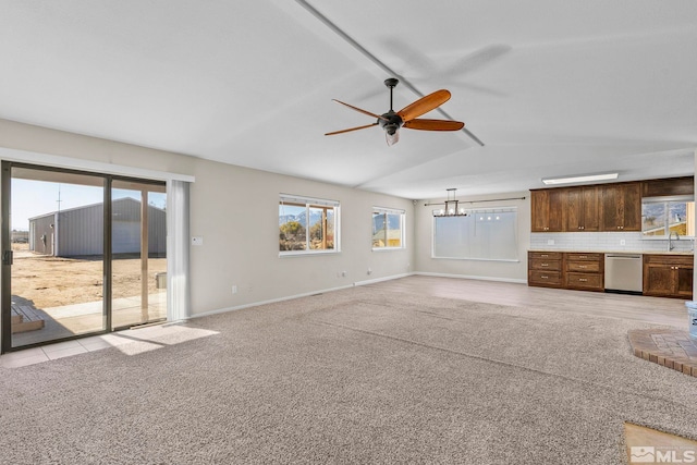 unfurnished living room featuring sink, light colored carpet, vaulted ceiling, and ceiling fan with notable chandelier