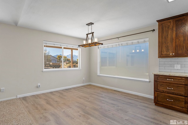 unfurnished dining area with light wood-type flooring and a chandelier