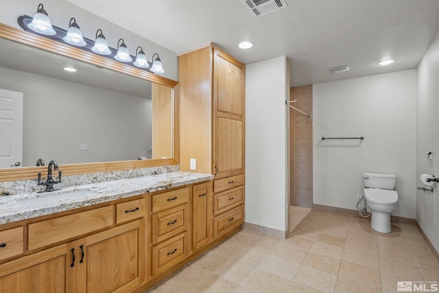 bathroom featuring tile patterned flooring, vanity, toilet, and tiled shower