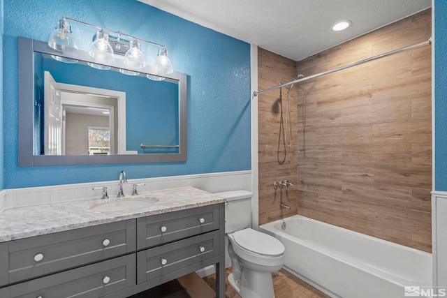 full bathroom featuring tiled shower / bath, a textured ceiling, toilet, and vanity