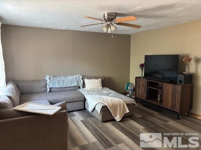 living room with dark hardwood / wood-style flooring, a textured ceiling, and ceiling fan