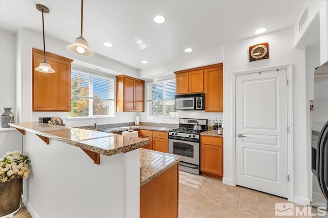 kitchen with kitchen peninsula, light stone counters, a kitchen breakfast bar, appliances with stainless steel finishes, and decorative light fixtures