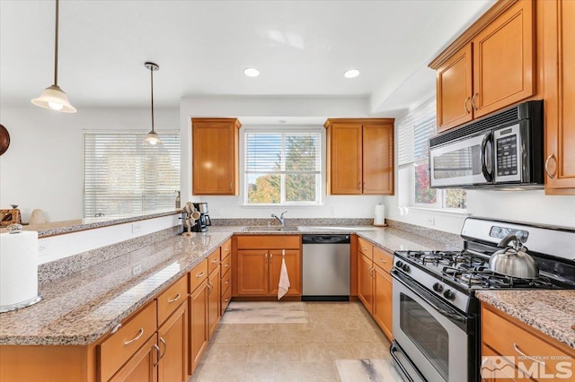 kitchen featuring a wealth of natural light, appliances with stainless steel finishes, hanging light fixtures, and light stone counters