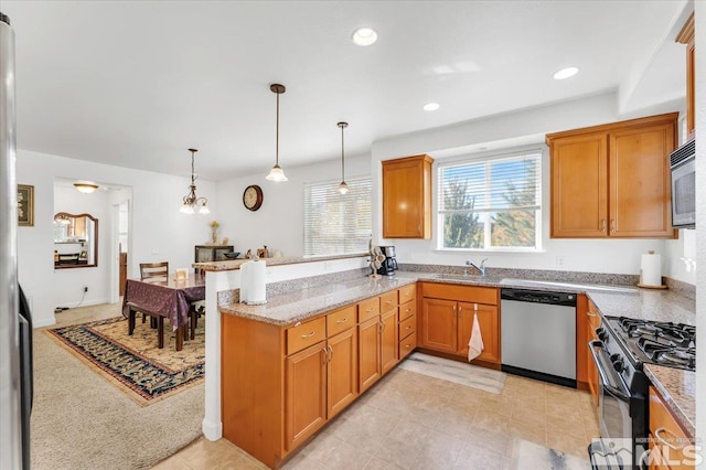 kitchen with light stone counters, appliances with stainless steel finishes, decorative light fixtures, sink, and kitchen peninsula