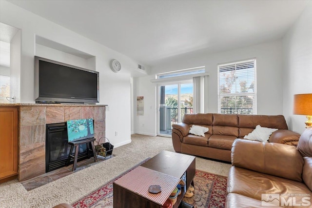 living room with a tile fireplace and light carpet