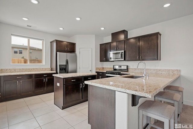 kitchen with a center island, a kitchen bar, appliances with stainless steel finishes, dark brown cabinets, and sink