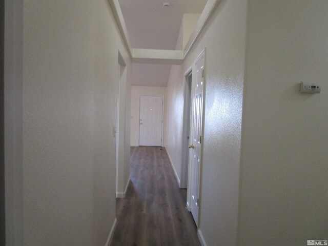 hallway with dark wood-type flooring and lofted ceiling