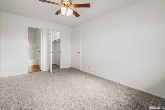 unfurnished bedroom with carpet, ceiling fan, a textured ceiling, and ensuite bath