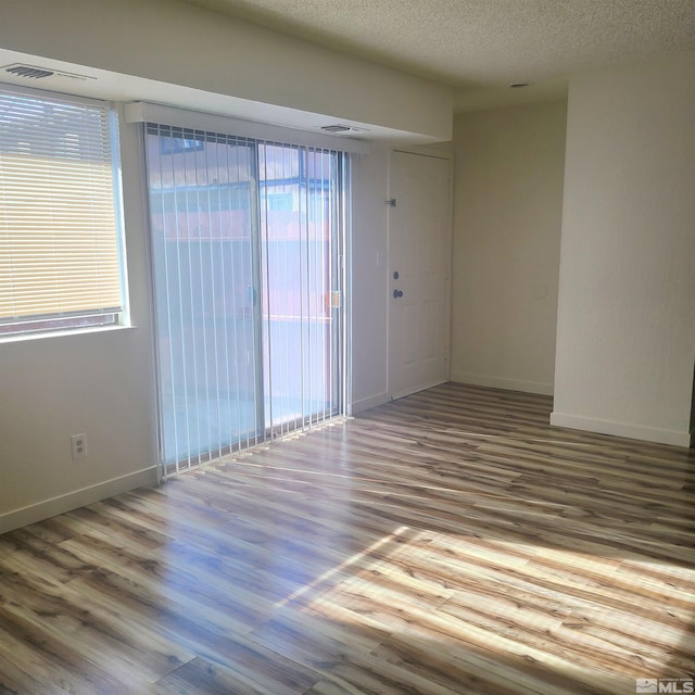 unfurnished room with light hardwood / wood-style floors and a textured ceiling