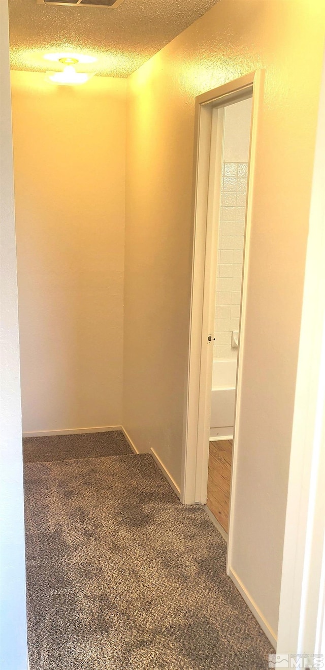 hallway featuring carpet and a textured ceiling