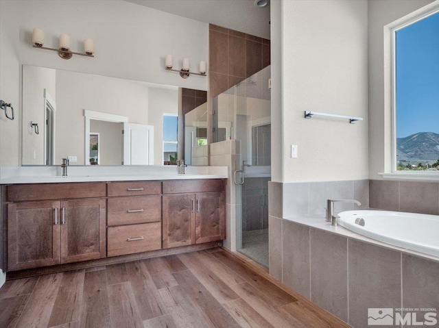 bathroom with a mountain view, wood-type flooring, vanity, and independent shower and bath