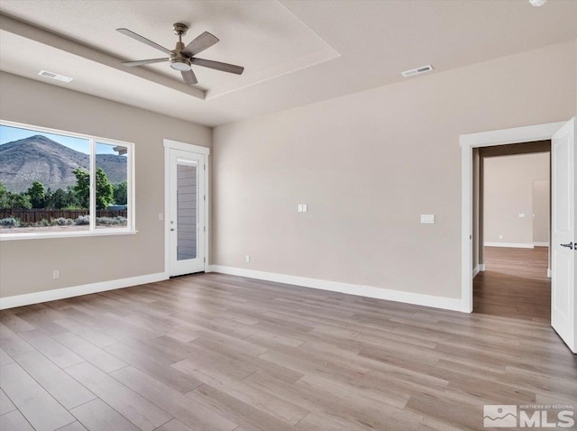 spare room with a mountain view, light hardwood / wood-style flooring, and ceiling fan