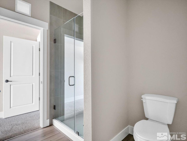 bathroom with toilet, a shower with shower door, and wood-type flooring