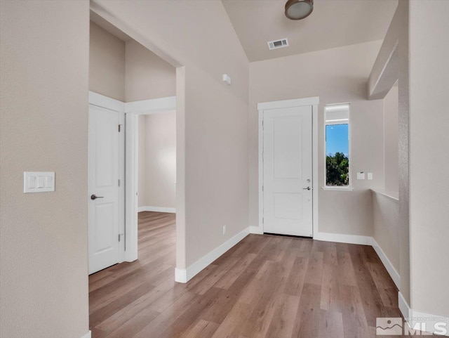 hall featuring lofted ceiling and light wood-type flooring